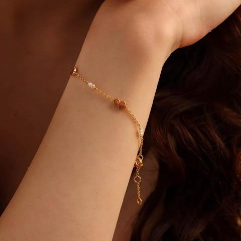 gold coloured bracelet, delicate looking, with small round pearls and flat pebble sections.