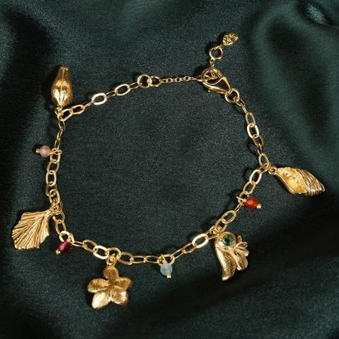 flat lay of charm bracelet on dark green satin