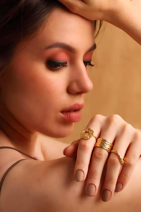 Young woman posing with multiple gold plated ring on hand over shoulder